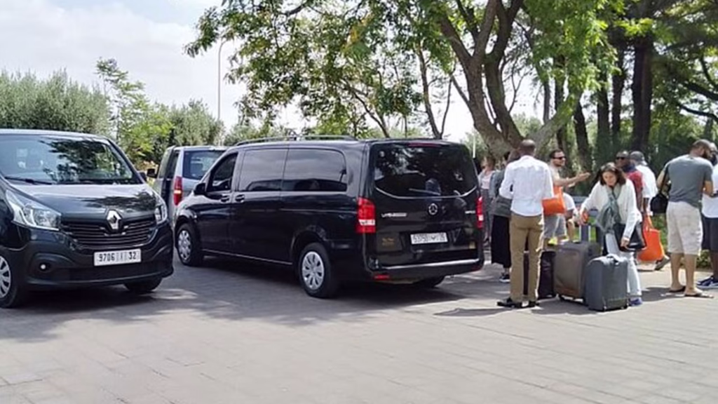 Group of travelers loading luggage into a private minivan at Marrakech airport for shared transfer