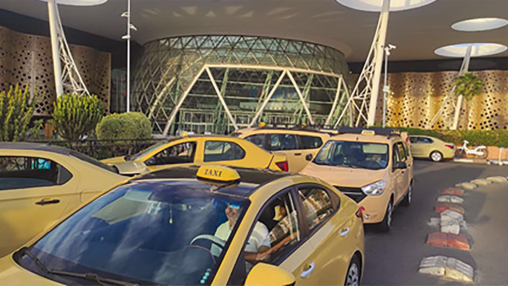 Official petit taxi rank directly outside Marrakech Menara Airport arrivals exit with beige taxis waiting